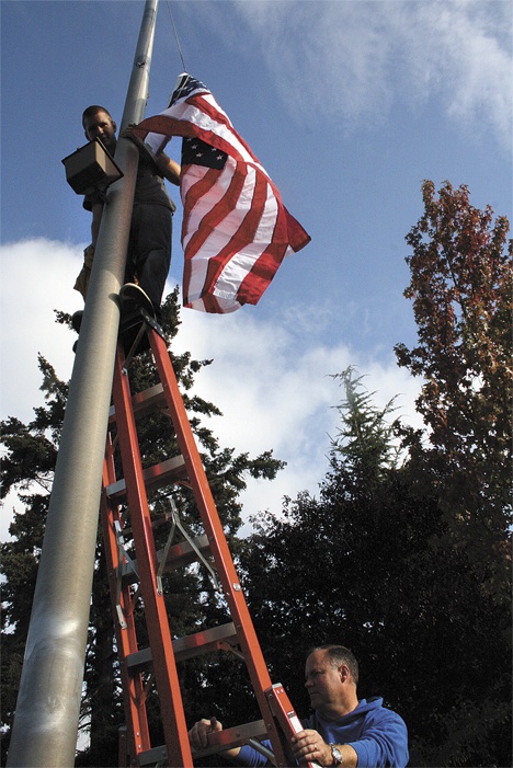 Randy Stone and Randy Long work on replacing the flags in front of the King County Aquatic Center.