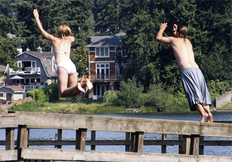 Pacific residents Mark and Amanda Steele jump off the pier at Steel Lake Park on Wednesday morning in Federal Way. The weather was expected to hit a high of 101 degrees Wednesday. The heat wave will continue at least through the weekend.