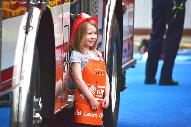 A girl wearing a fire department hat stands in front of a South King Fire and Rescue engine during the annual Touch-a-Truck event on Saturday at Town Square Park.