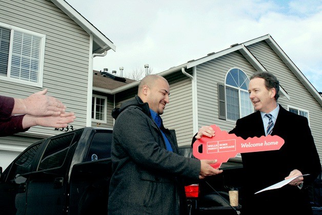 Marcos Garcia (center) receives the 'key' to his new mortgage-free home from Jonathan Taylor