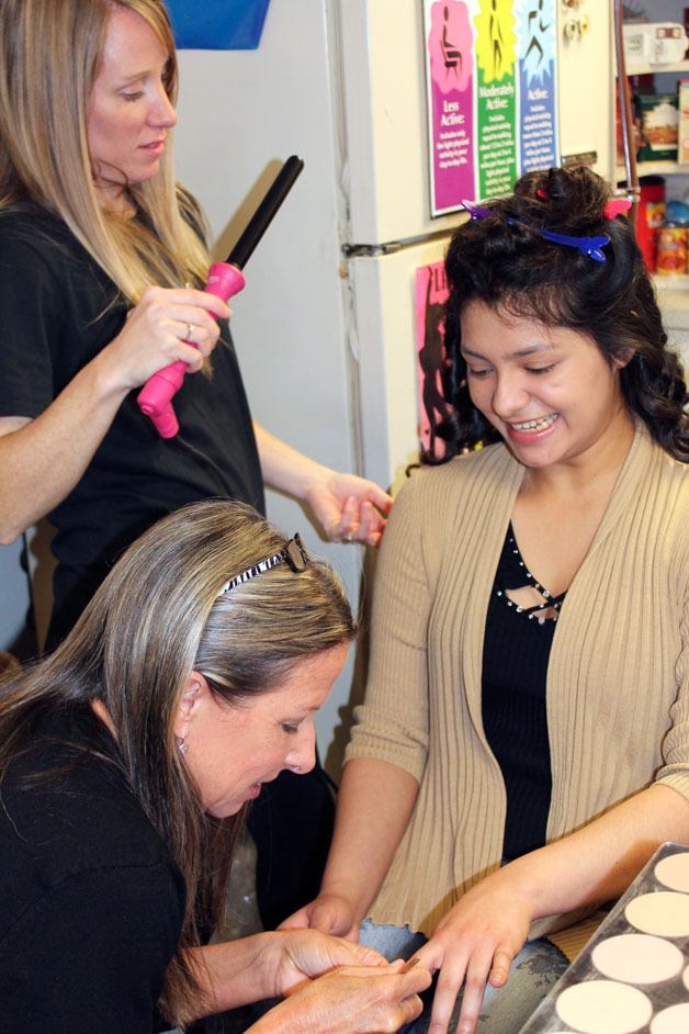 Federal Way High School senior Elsy Alemam (right) smiles as Wendy McIntosh curls her hair and Dayna Farlow paints her nails on Saturday afternoon at the school before the prom.