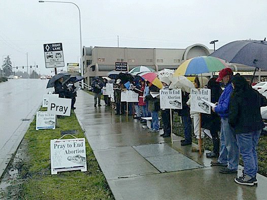 A group of people protesting abortion stand in front of the Planned Parenthood clinic in Federal Way. The campaign