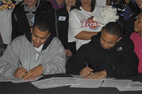 Federal Way High School basketball players Cole Dickerson (left) and Isiah Umipig sign their national letters of intent Thursday at the school.