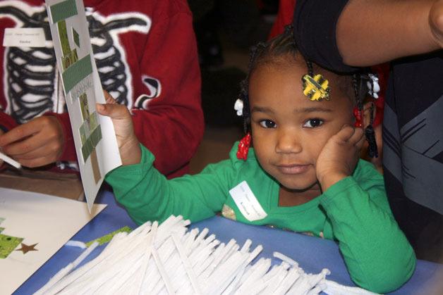 A girl holds up a Christmas decoration she made during the annual Adopt-A-Family event at Grace Church on Dec. 12