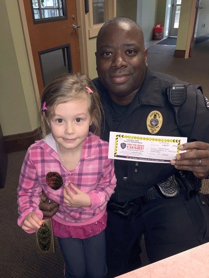 Federal Way police officer Thaddeus Hodge presents 5-year-old Harlee Hansen with the first Positive Ticket.