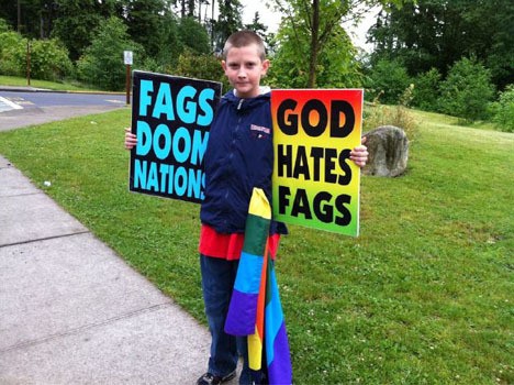 A boy holds signs on behalf of Kansas-based Westboro Baptist Church during a protest Sunday morning outside Mars Hill church’s Federal Way branch