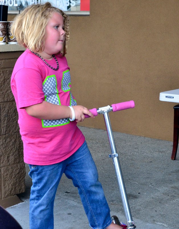 Kaylin Burns rides her pink scooter during a benefit car wash in her honor on Sunday. Kaylin has two hemangioma tumors she was born with and proceeds from the event will help her family pay for her medical care.