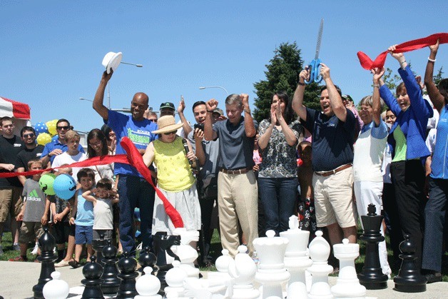 Federal Way Mayor Jim Ferrell holds up scissors as the crowd cheers following a ribbon-cutting ceremony at the new Town Square Park on Saturday afternoon.