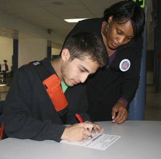 Monica Bolden helped Federal Way High School senior Pablo Queredo fill out a voter's registration in the cafeteria on Monday.