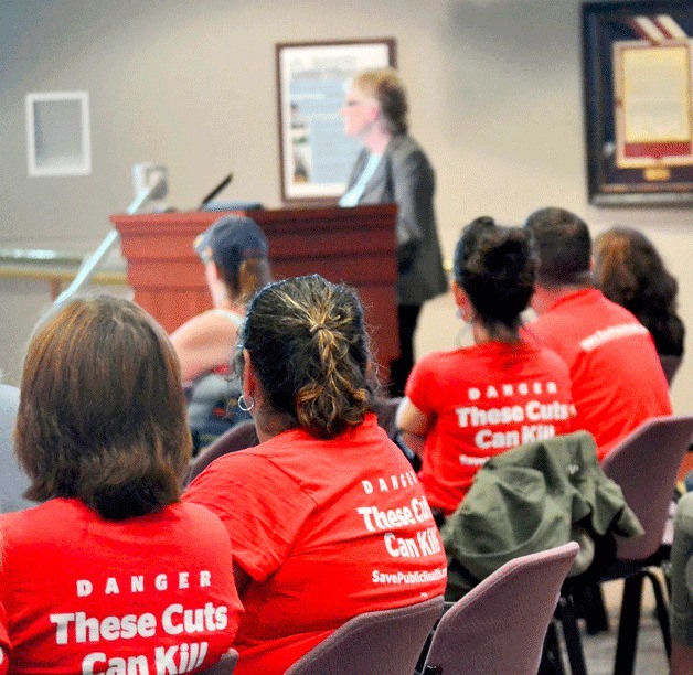 Public Health Center supporters wear T-shirts that state “Danger