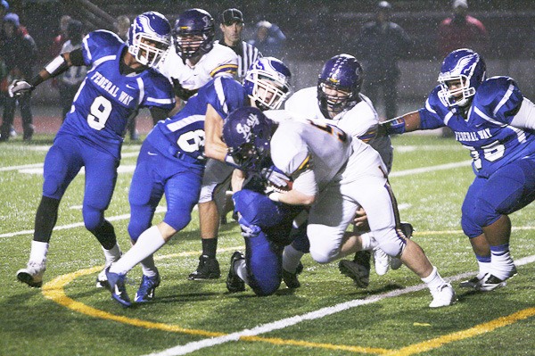 Federal Way senior Aaron Persinger makes a tackle Friday against Issaquah while Marcus Fielder (9) looks on at Federal Way Memorial Stadium. The Eagles beat Issaquah 24-14 to advance into the state playoffs.