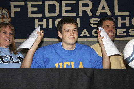 Federal Way High School senior Kelyn Rowe holds up his national letter of intent to play soccer at UCLA Wednesday beside his parents