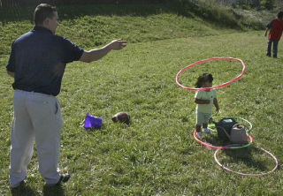 Carlos Cardenas tosses a hula hoop over his daughter