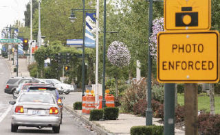 A red light camera (surrounded by orange construction barrels) at Pacific Highway South and South 320th Street in Federal Way. Tickets for running a red light will cost violators $124.