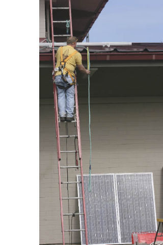 Alan Clark of Brothers Electric Solar makes a measurement while preparing to install a solar power demonstration on the roof of Thomas Jefferson High School last week. The equipment will convert light directly into energy