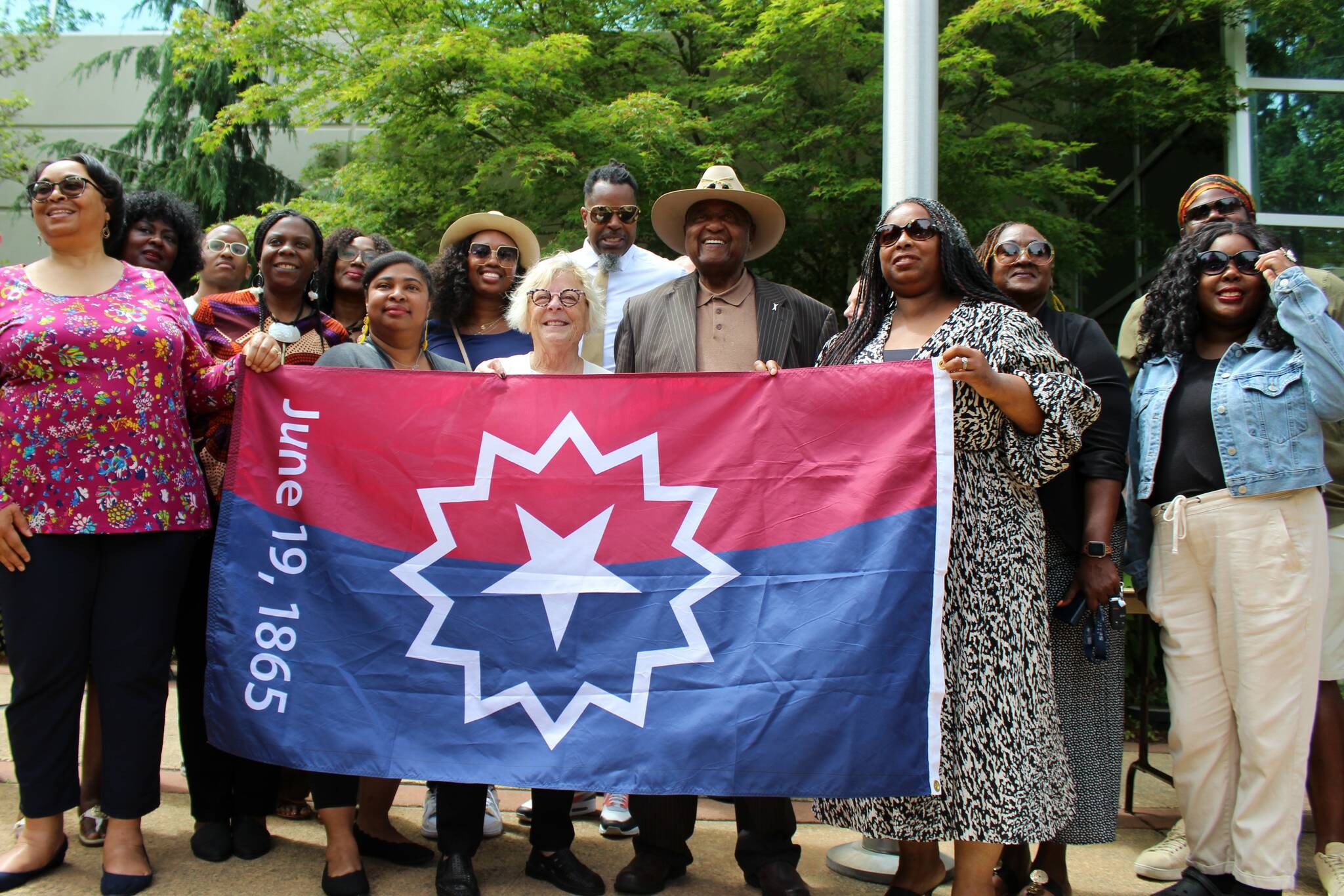 City leaders and community members hold the Juneteenth flag outside city hall. Alex Bruell / The Mirror