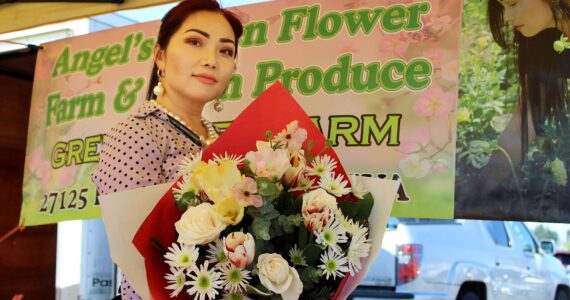 Angel Vue shows off one of the flower bouquets for sale at her storefront at last year’s Federal Way Farmers Market. File photo