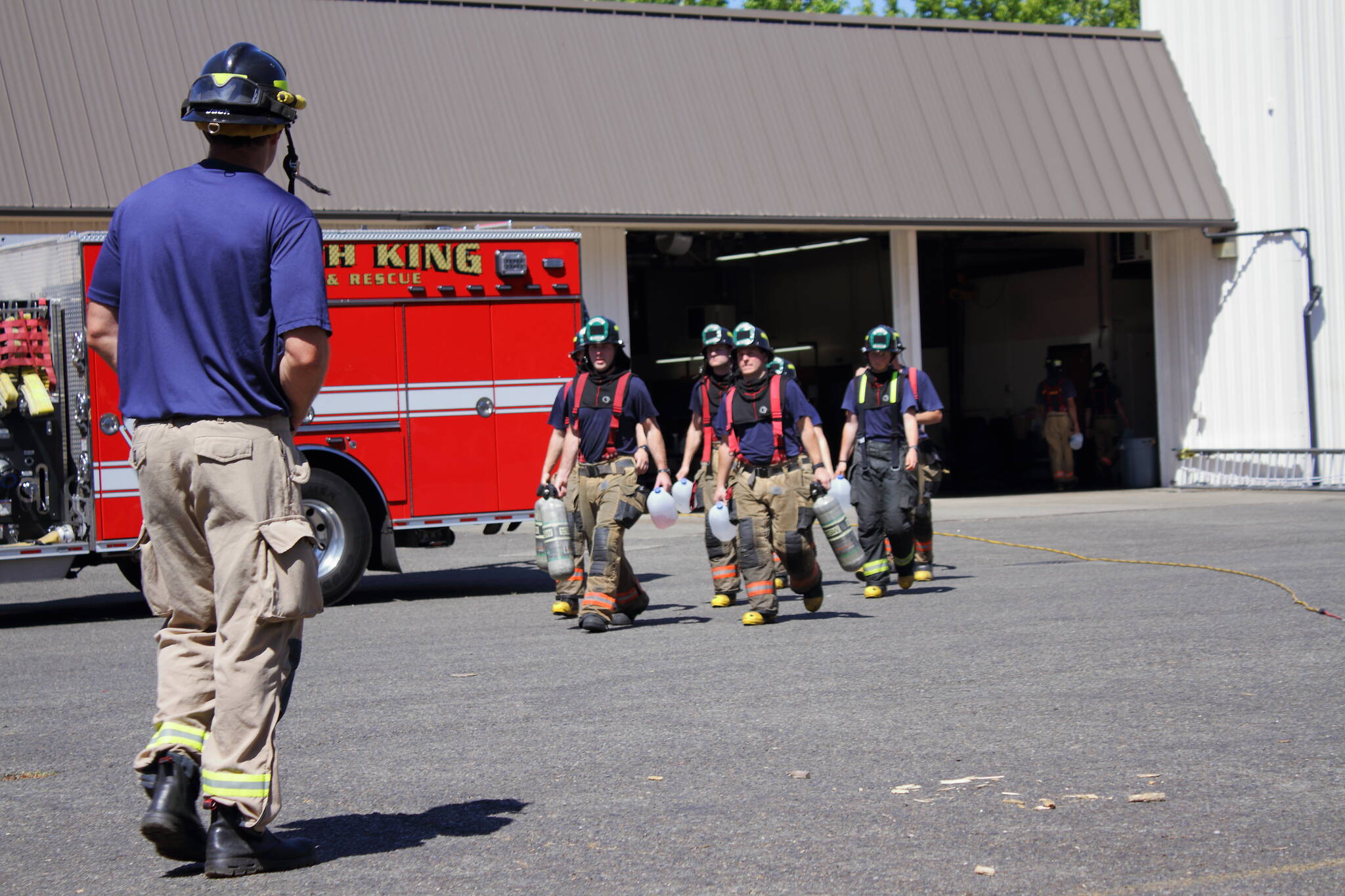 Driver Engineer Brian Jack heads toward a group of newly graduated probationary firefighters during their post-academy training at South King Fire. Photo by Keelin Everly-Lang / The Mirror.