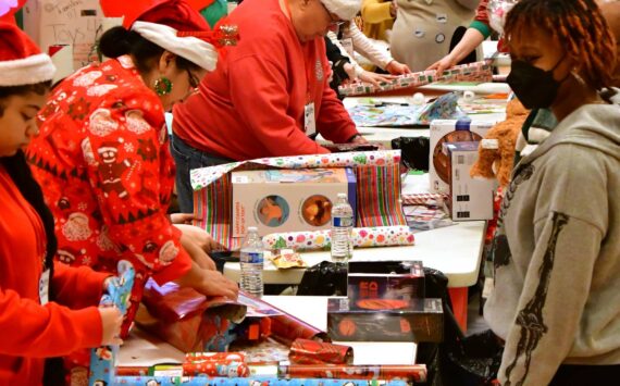 Volunteers partner up with parents and families to wrap presents and ensure that every kid in Federal Way has access to a joyful holiday at the annual Federal Way Cares for Kids event on Dec. 21. Photo by Bruce Honda